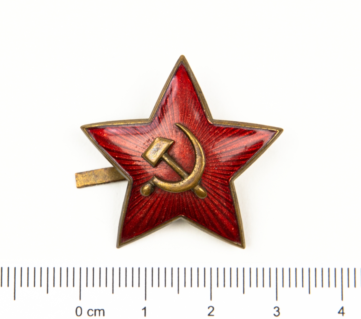 Mössmärke i form av en 5-uddig stjärna. På märket hammaren och skäran. Från Ryssland.