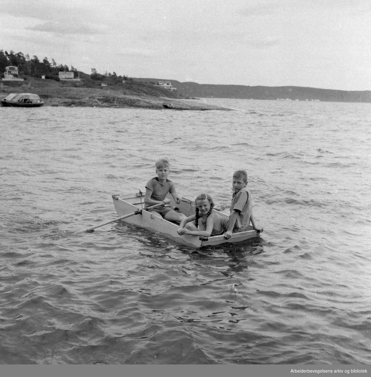 Mange tilbringer sommerferien på Langåra. De tre i jolla er: Rolf Erik Christiansen, Astrid Hagene og Tore Kristiansen. Juli 1958