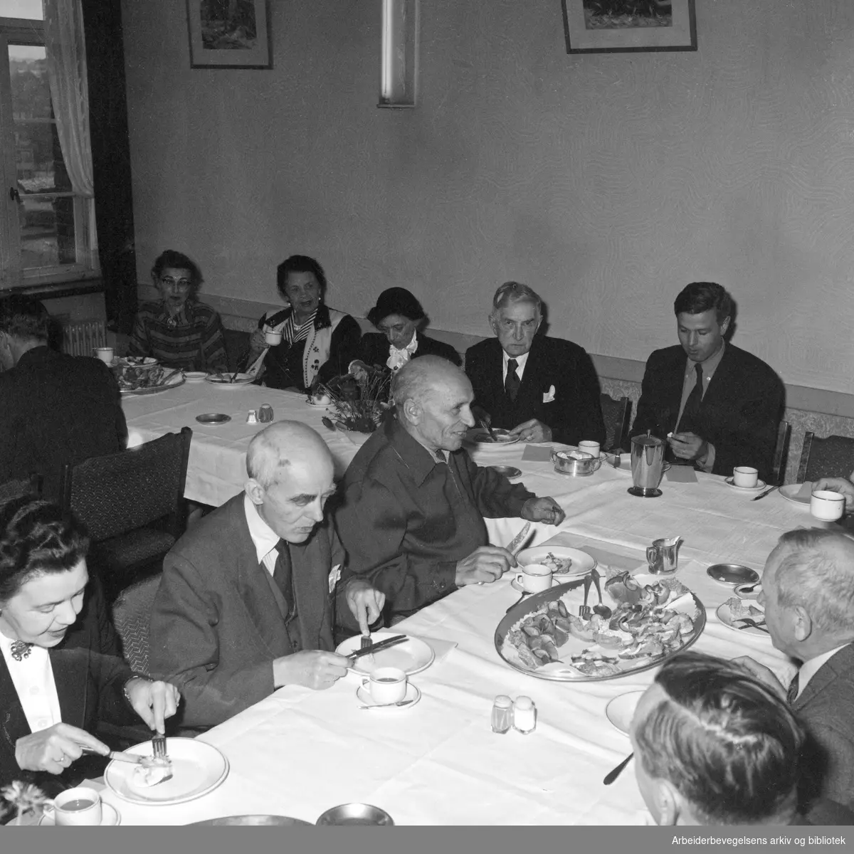 Johan Falkberget fyller 75 år. Arbeiderbladets redaksjon samlet på restaurant Stratos. Blant andre: Ragna Hagen, Rachel Grepp, Johan Falkberget og Per Wiedsvang. Martin Tranmæl i forgrunnen. Oktober 1954.
