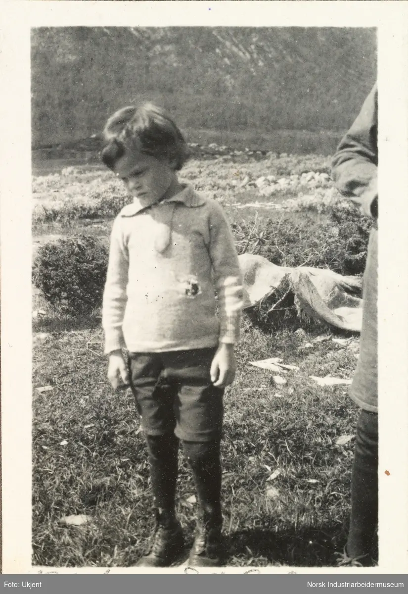Briskeroe på Møsstrond. En ung Anton Poulsson i shorts og strømper står utendørs