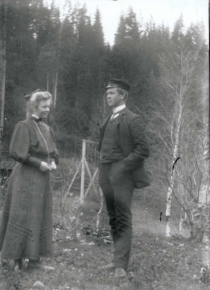 Signe Rydgren og Harald Rydgren i bestyrervillaens hage på Kistefos Træsliberi. Busker og trær i bakgrunnen.