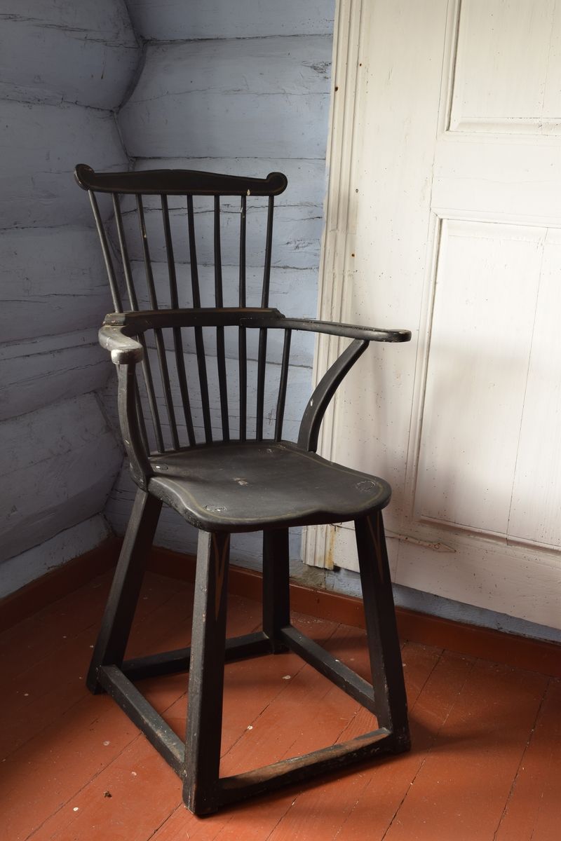 Sortmalt høyrygget stol med dreide ben og spiler i ryggen. formet som en pinnestol med høyere rygg og armlener