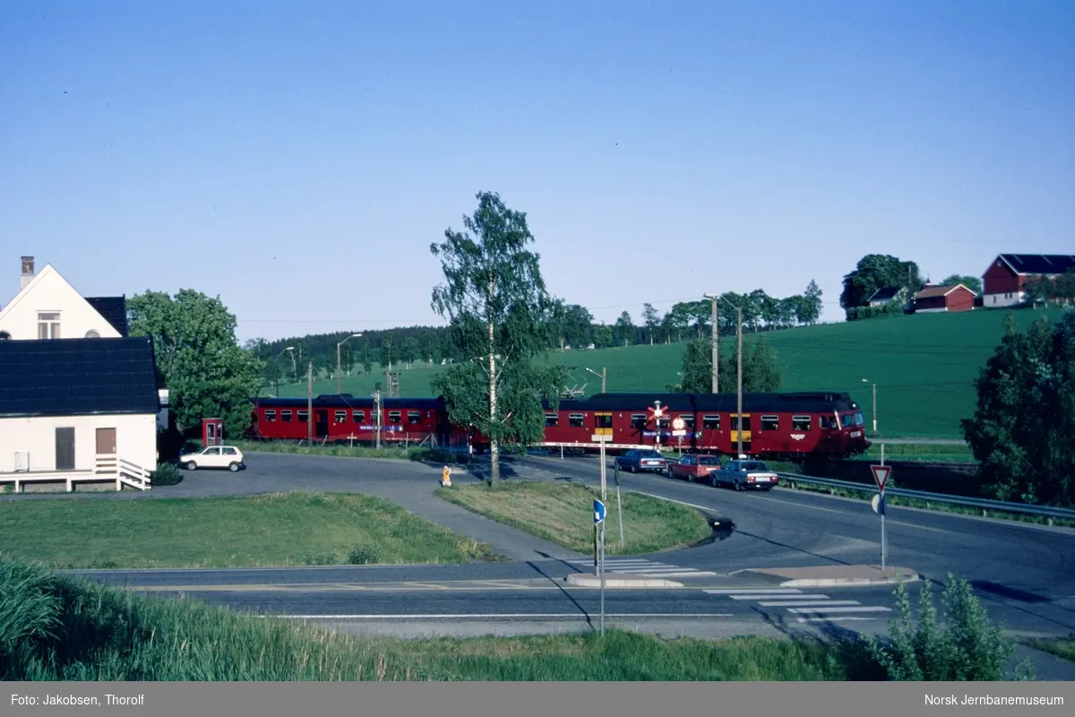 Lokaltog til Moss, tog 131, med motorvognsett type 69 passerer planovergangen på Holstad stasjon på Østfoldbanen