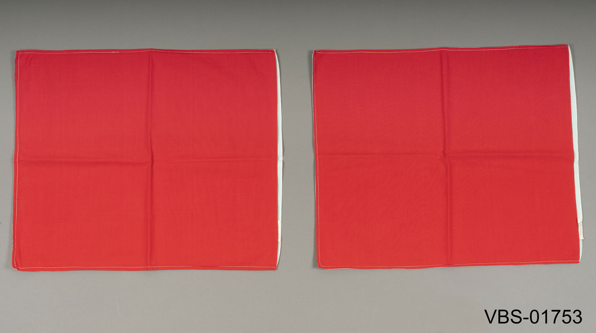 To identiske rektangulær nakkeputer i bomull med åpning i den ene langsiden for å legge inn pute (uten bånd eller knapper). 
Den ene siden er rød og den andre lys grønn.