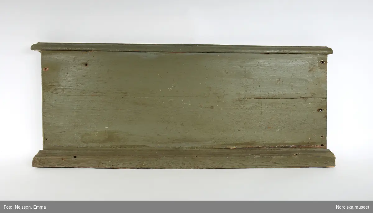 Fotsockel, 17 delar, varierande längder, av furu, målad i grågrön oljefärg, omkring 1740. Slät, med vulst upptill och profilering nedtill.

Anm: Partiellt färgbortfall och skador. En sockel har gått mitt itu, flera socklar kompletterade.
/Anna Arfvidsson Womack 2021-07-19