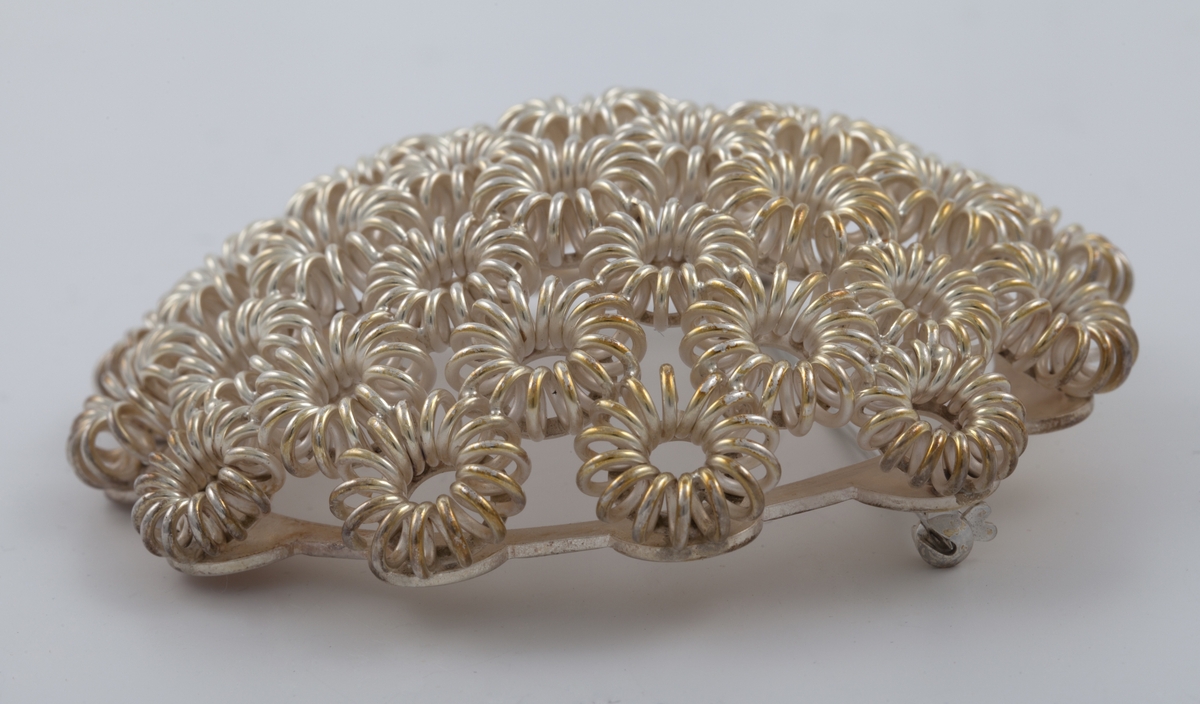 Rund buet brosje i sølvfiligran, bestående av runde stiliserte blomsterformer.