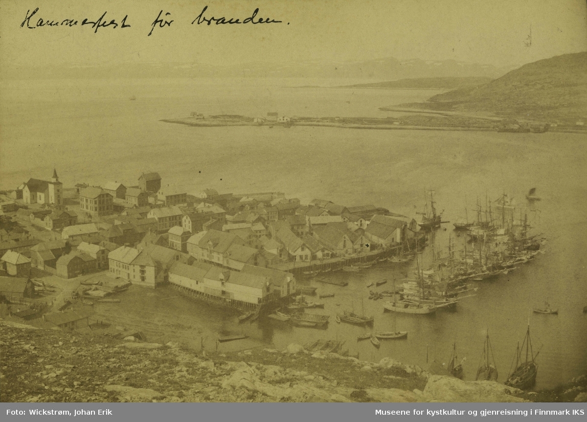 Bildet av Hammerfest før bybrannen 1890. Den tidligere kirken viser dette. Til høyre ser man havna med båter, kaianlegg og pakkhus. I bakgrunn til høyre ser man Fuglenes.