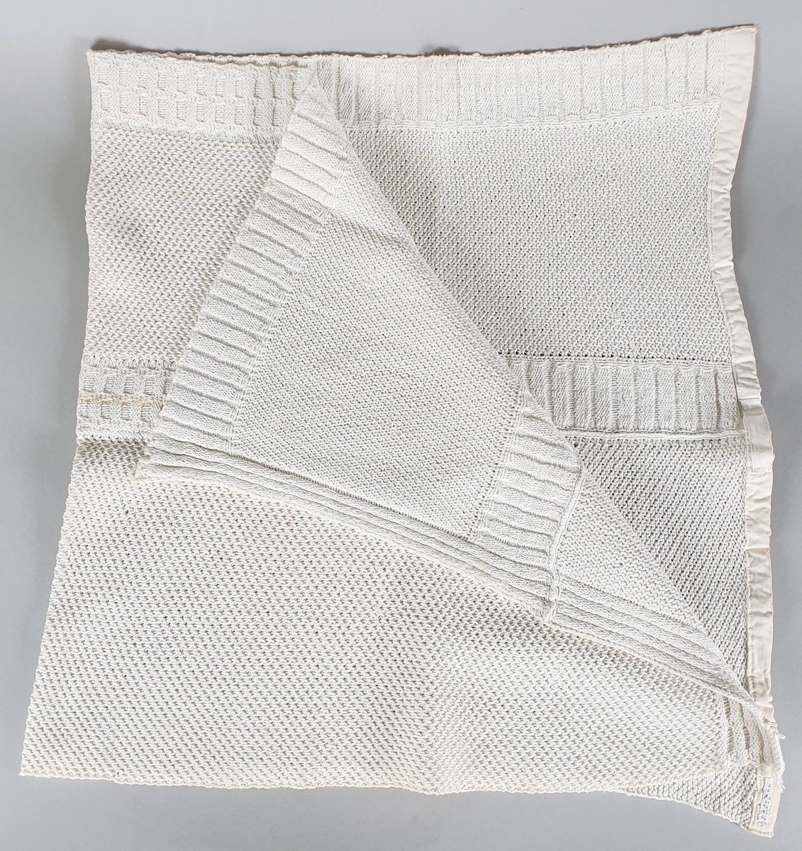 Tre strikkede kjøkkenhåndklær av bomull, kantet med bomullsbånd.