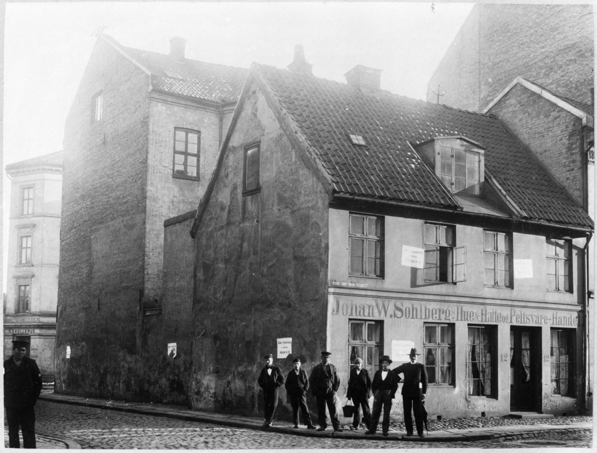 Menn stilt opp foran bygning i Karl XIIs gate. Skilt: Johan W. Sohlbergs hue&hatte ogpelsvare-handel.