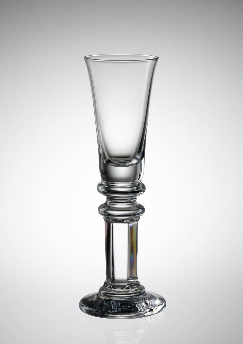 Formgivare: Gunnar Cyrén. Glaset har en klockformad kupa. Benet är pressat, med en imitation av en facettslipning.

