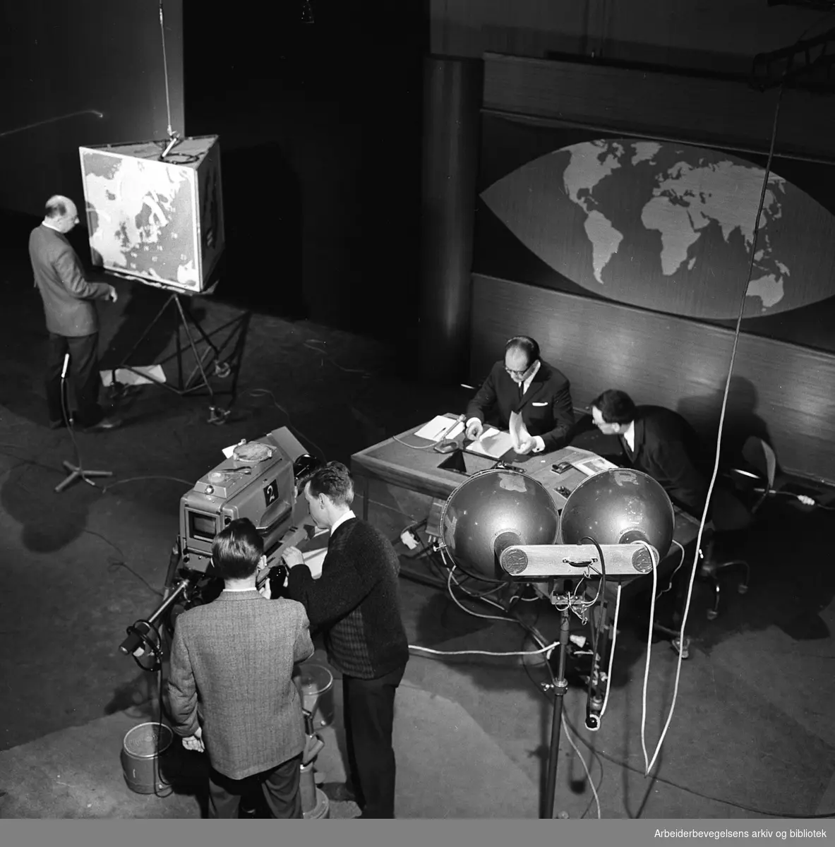 Programleder Per Øyvind Heradstveit forbereder seg til sending av Dagsrevyen. Til venstre står meteorologen med værkartet. Mai 1963