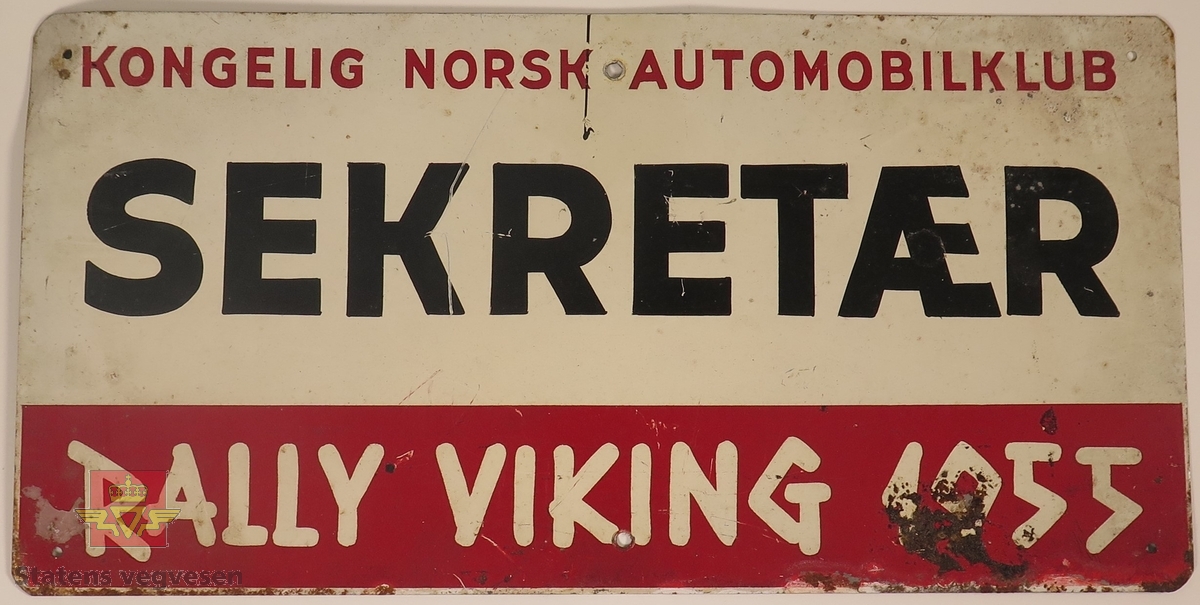 Hovedsakelig hvitt metallskilt med et mindre rødt markeringsområde. Det er laget til 6 festehull på skiltet, 3 nede og 3 oppe.
Påskrift: KONGELIG NORSK AUTOMOBILKLUB, SEKRETÆR, K.N.A. RALLY VIKING 1955