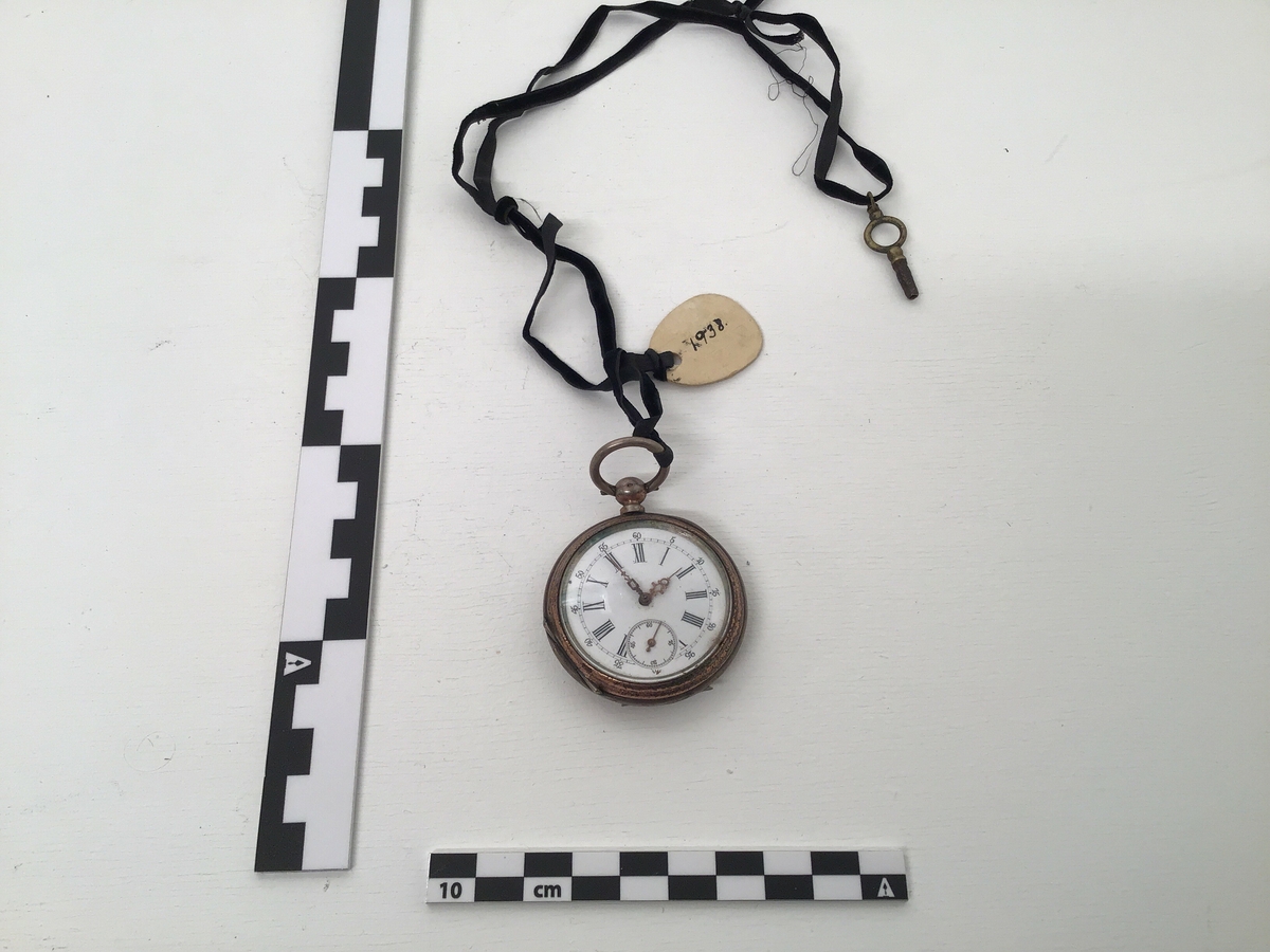 Uret er eit nøkkelur og nøkkelen heng i eit silkeband saman med klokka.Visarane på klokka er fint utforma og vetlevisaren er pynta med ein blank stein.