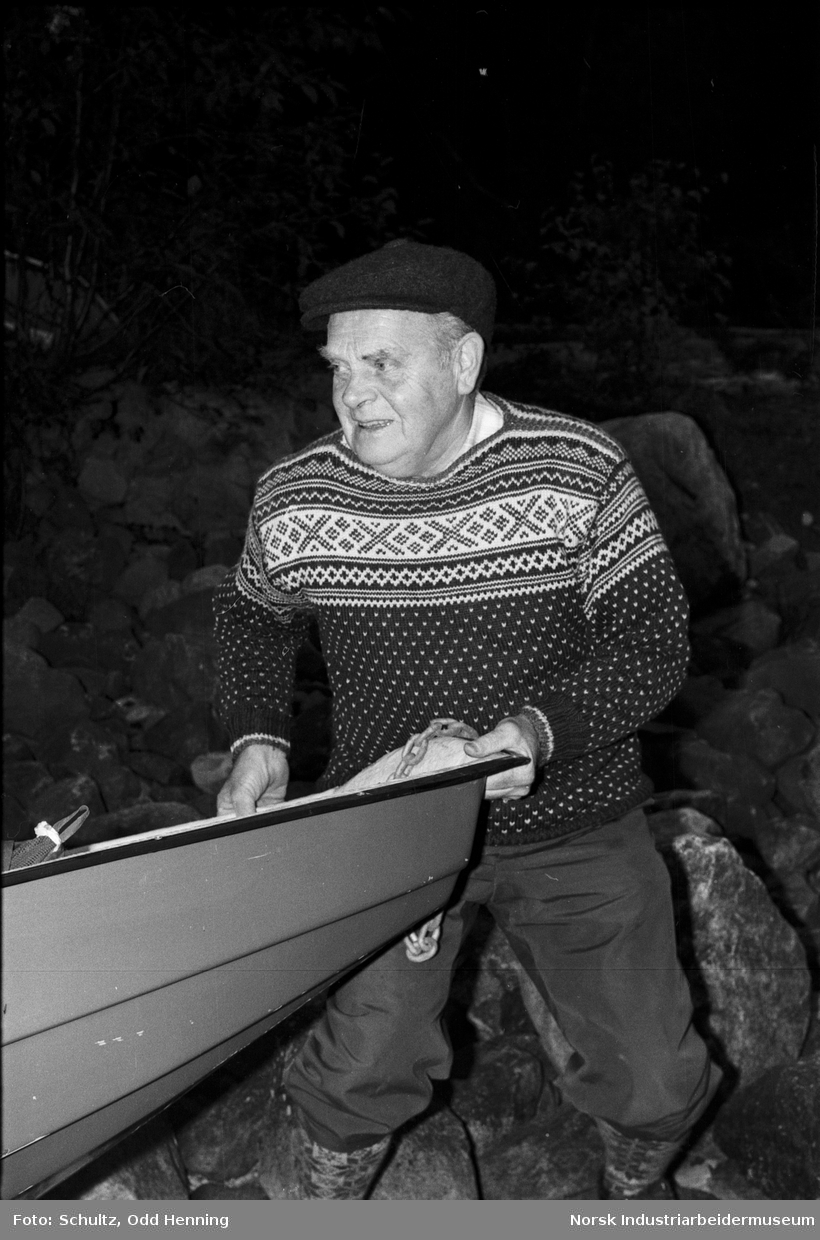 Mann som setter båt på vannet for å dra på fisketur.