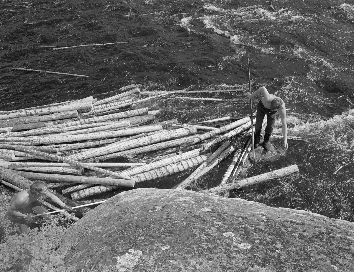 Sluttrensk i elva Stor-Grøna i Trysil, Hedmark. Fløter i arbeid med å løsne tømmer som har bygd seg opp til en tømmerhaug langs elvebredden.