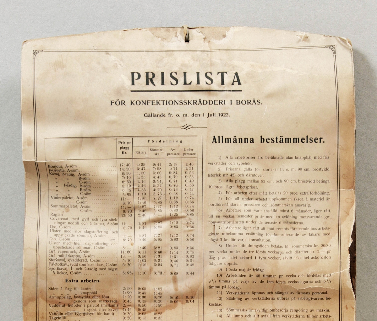 Prislista för konfektionsskrädderi i Borås. Rektangulär. Papper limmat på hård kartong. Med allmänna bestämmelser och gällande från och med 1 juli 1922. Fuktskador.

Funktion: Prisinformation