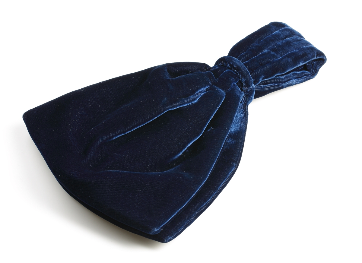 Aftonväska av blå silkesammet. Påsform med två fack, invändigt klädd med ljusblå taft, stängd med blixtlås. Buren av författarinnan Elin Wägner vid hennes inträde i Svenska akademien år 1944. 

Inskriven i huvudboken år 1949.
