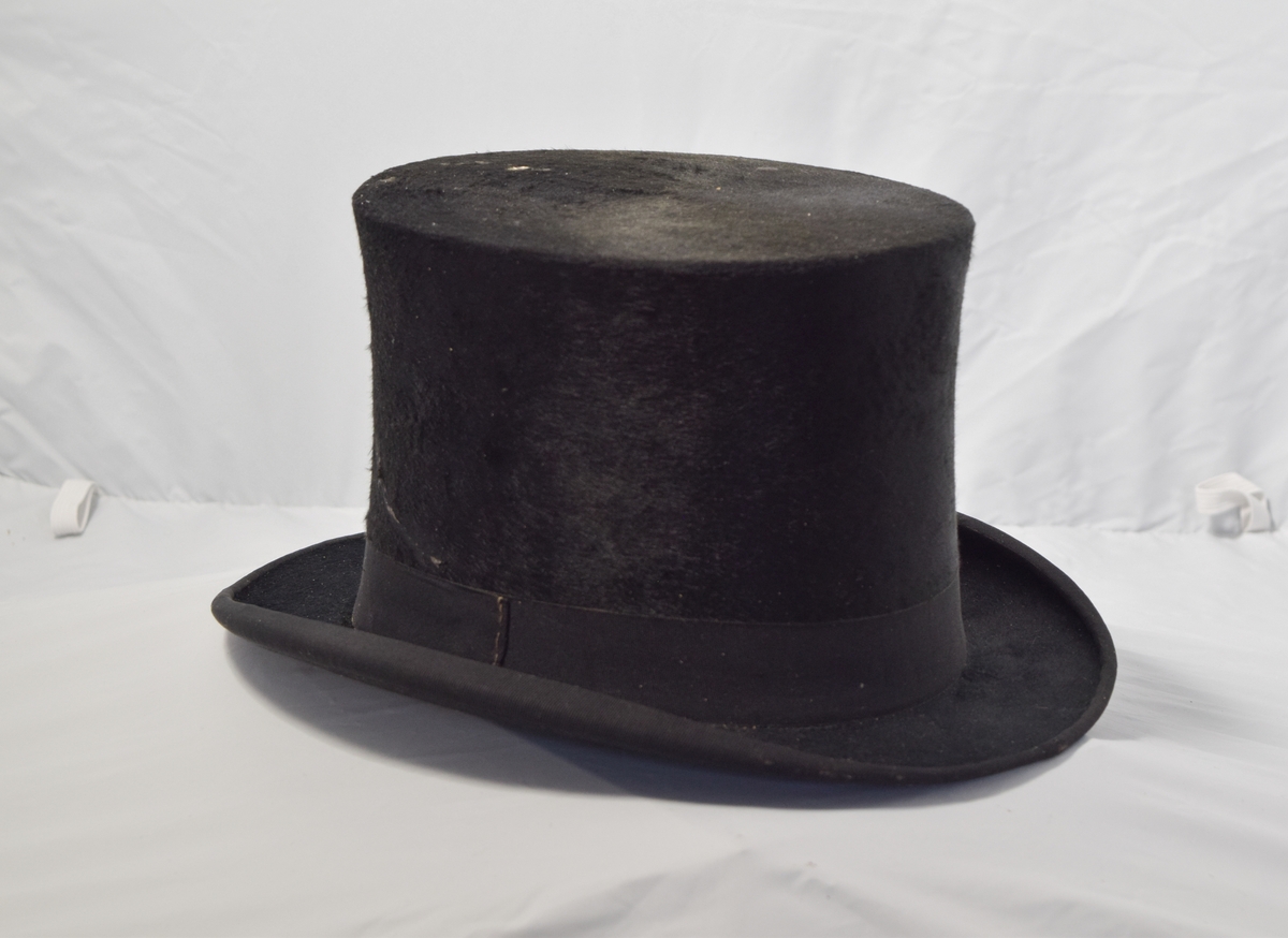 Svart og lav flosshatt. Hatten har motivstempel på innsiden av hatten.