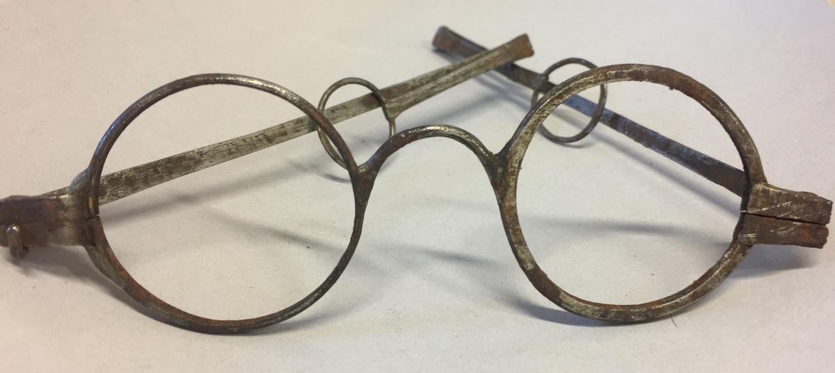 Brillene er i jern og dei er heimesmia. Faldbare, ledda stengar. Innfatninga har ikkje glas.