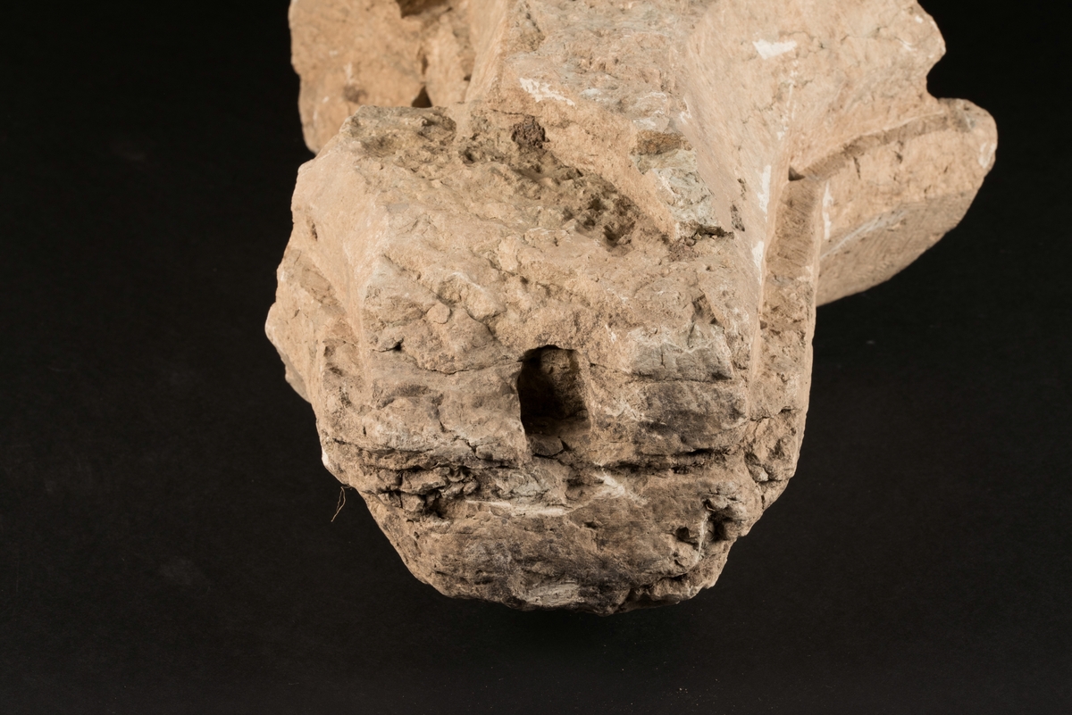 Del av masverk tillverkad av huggen kalksten.
Stenen är bevarad i sin fullständiga längd med näsa åt ena hållet. Åt andra hållet finns två avbrutna utskott riktade mot varandra. Uthuggen fals för fönsterbågar.
