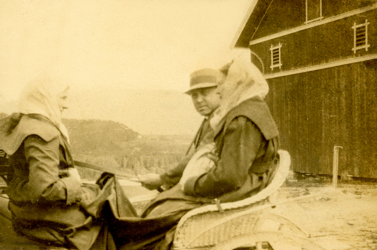 Halvor E. Skogen og kona Anne Kittilsdotter sitjande i firehjuls-trille i tunet heime på nedre Torstveit.  Tatt ein gong i 1920-åra.