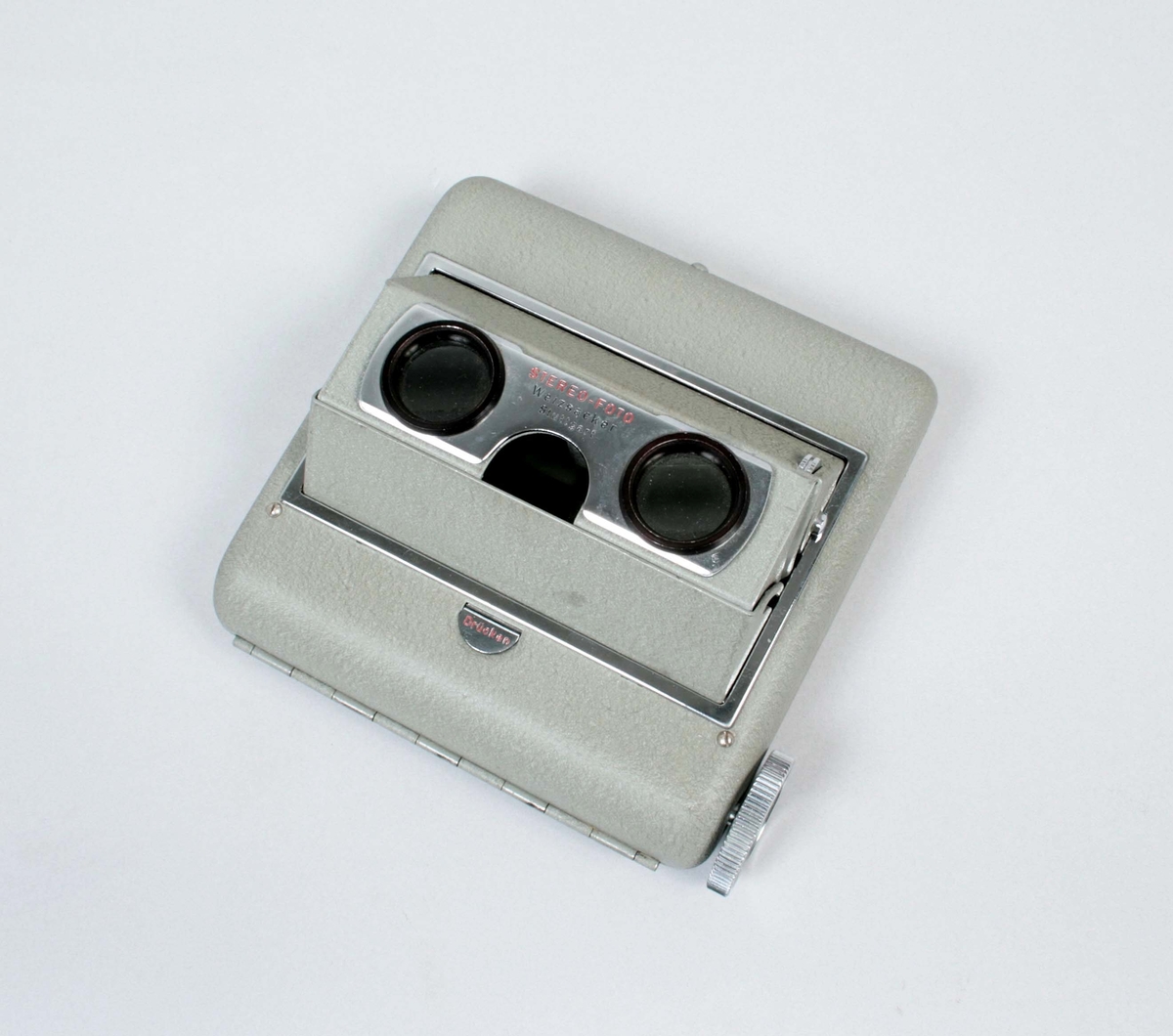 Stereokamera. Filmer kan visas i 3D (rumsperspektiv där längd, bredd och djup uppfattas). Skåpet är lackerat i grögrön plåt, med två tiitthål och  
på motsatta sidan, en skärm av plast. Inne i lådan, roterar en film som exponeras mot titthålen. Titthålen justeras, så att den tredimensionella bilden uppstår. För 120 mm:s diarulle (50 x 80 mm). Förvaras i svart plastfodral med dragkedja. Märkt: Stereo-foto Weizsäcker Stuttgart

Funktion: Att titta på stereoskopiska bilder eller 3D-bilder. Även film kan betraktas i stereokameror