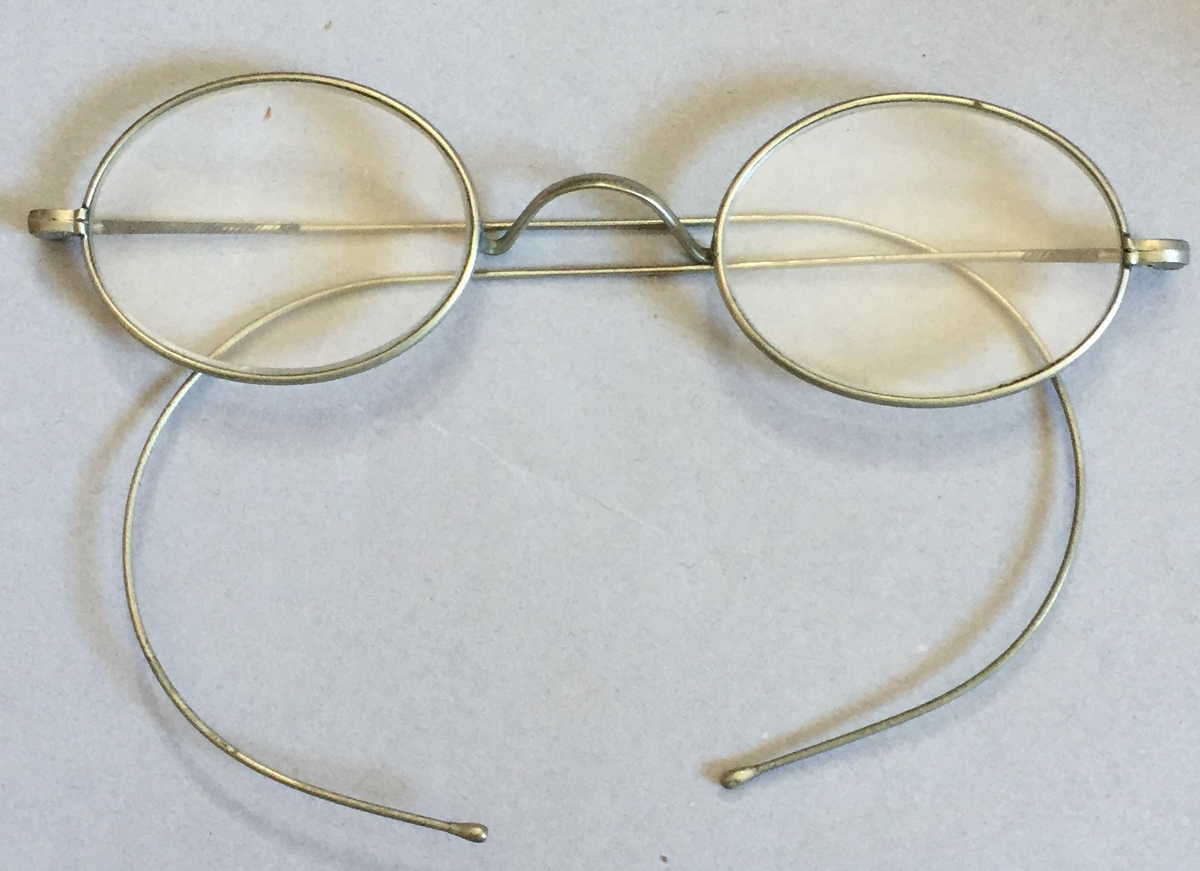 Briller med stålinfatning. Etui i metall trekt med stoff. Etuiet er mykje slite.