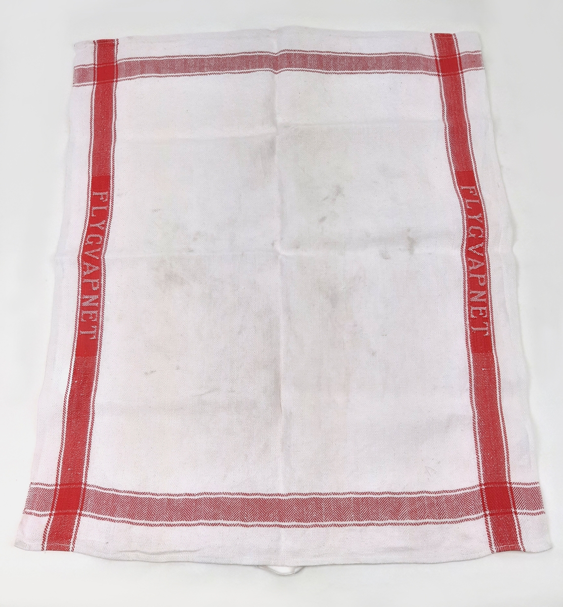 Linnehandduk i vit textil med röda bårder, samt invävd text "FLYGVAPNET".