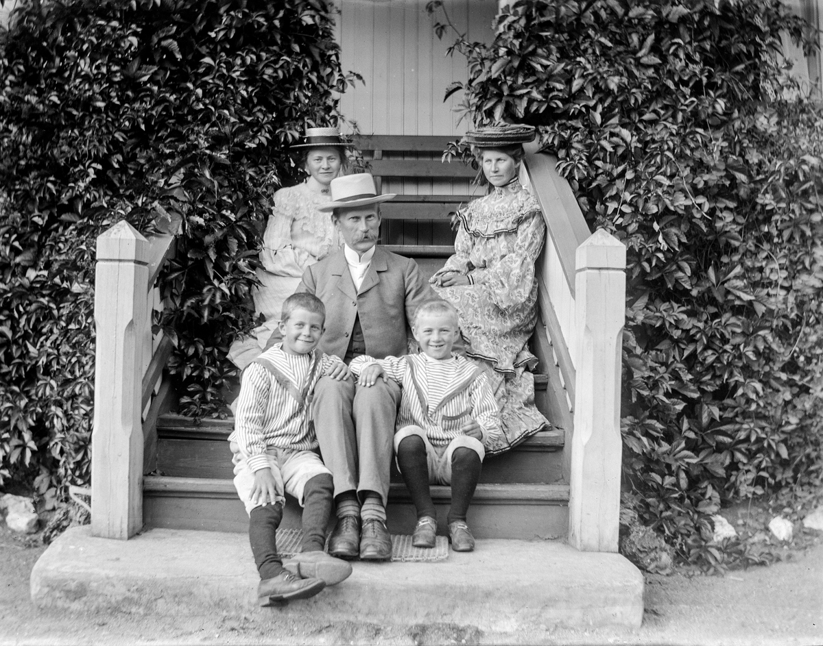 Tre voksne og to barn på en trapp.