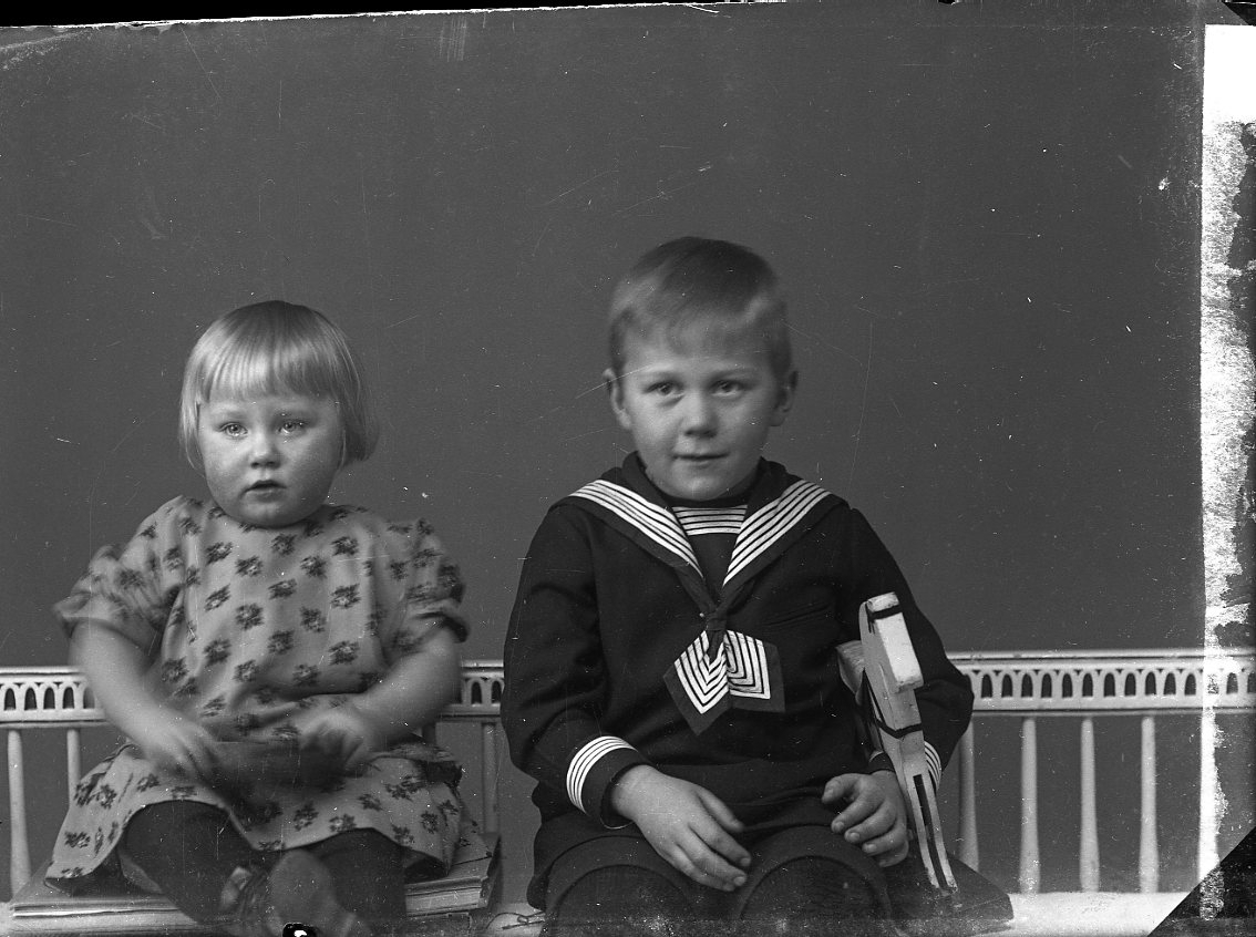 Två små barn sitter i en soffa av gustaviansk stil. Det är syskonen Ingeborg och Karl Erik Andersson i Alboga.