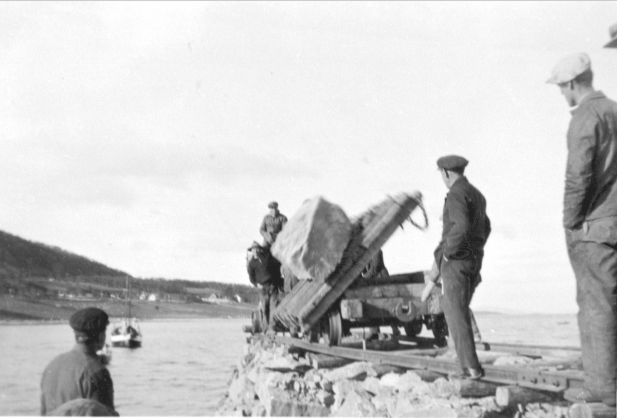 Arbeidslag bygger steinmoloen på Lundenes. Stein tippes av skinnegående vogn.