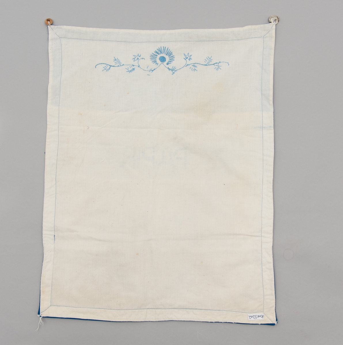 Hvit og blå veggoppbevaring/oppbevaringspose. Den har lommer til papir, poser, kork og hyssing. Blått korssting broderi.