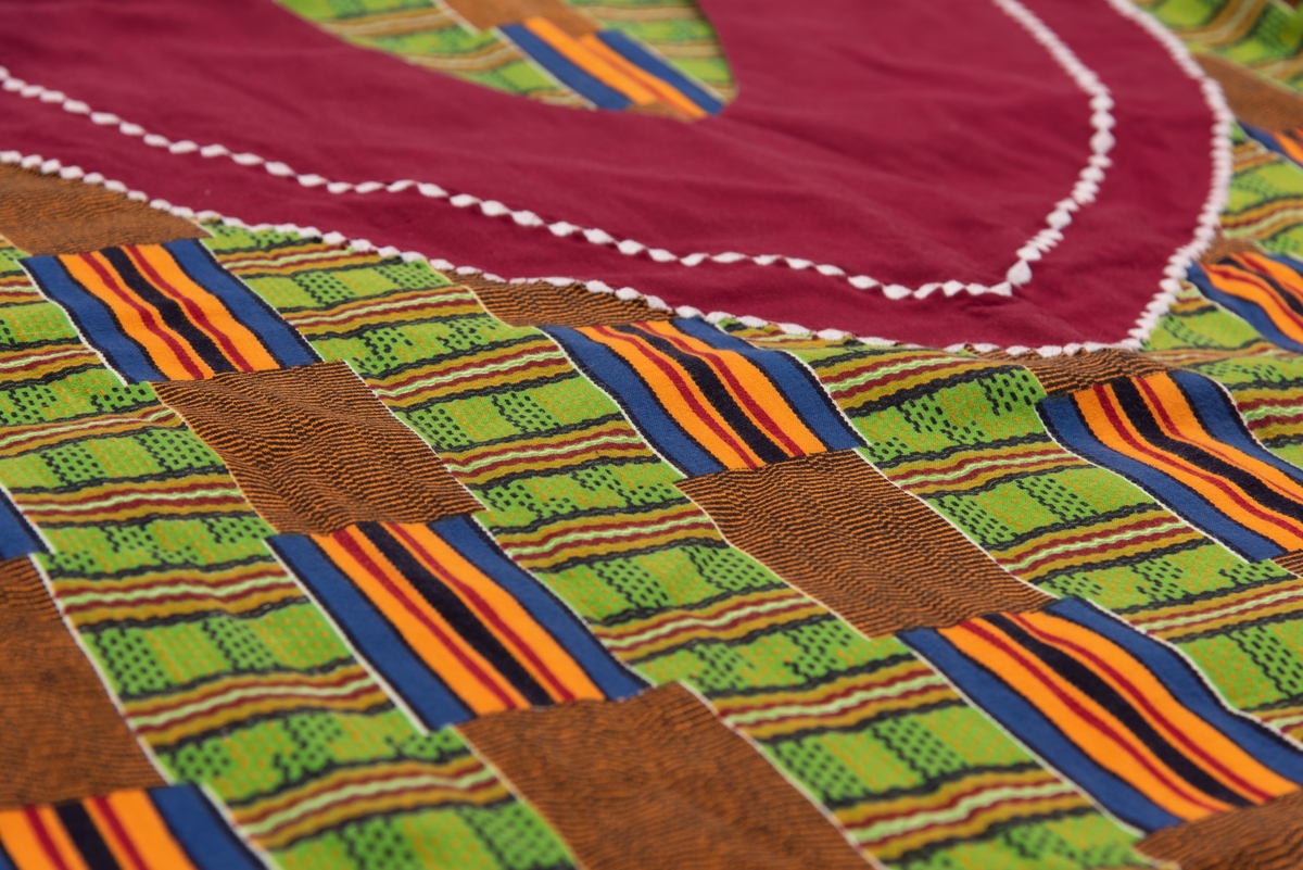 En afrikansk mangemønstret og mangefarget kjole og et rødt sortmønstret skjerf. 
Kjolen ble brukt som UNICEFs regiondirektør for Vest- og Sentral-Afrika i perioden 1994-98. I Kvinnemuseet samling inngår også foto av Torild Skard på jobb med denne kjolen og skjerfet.