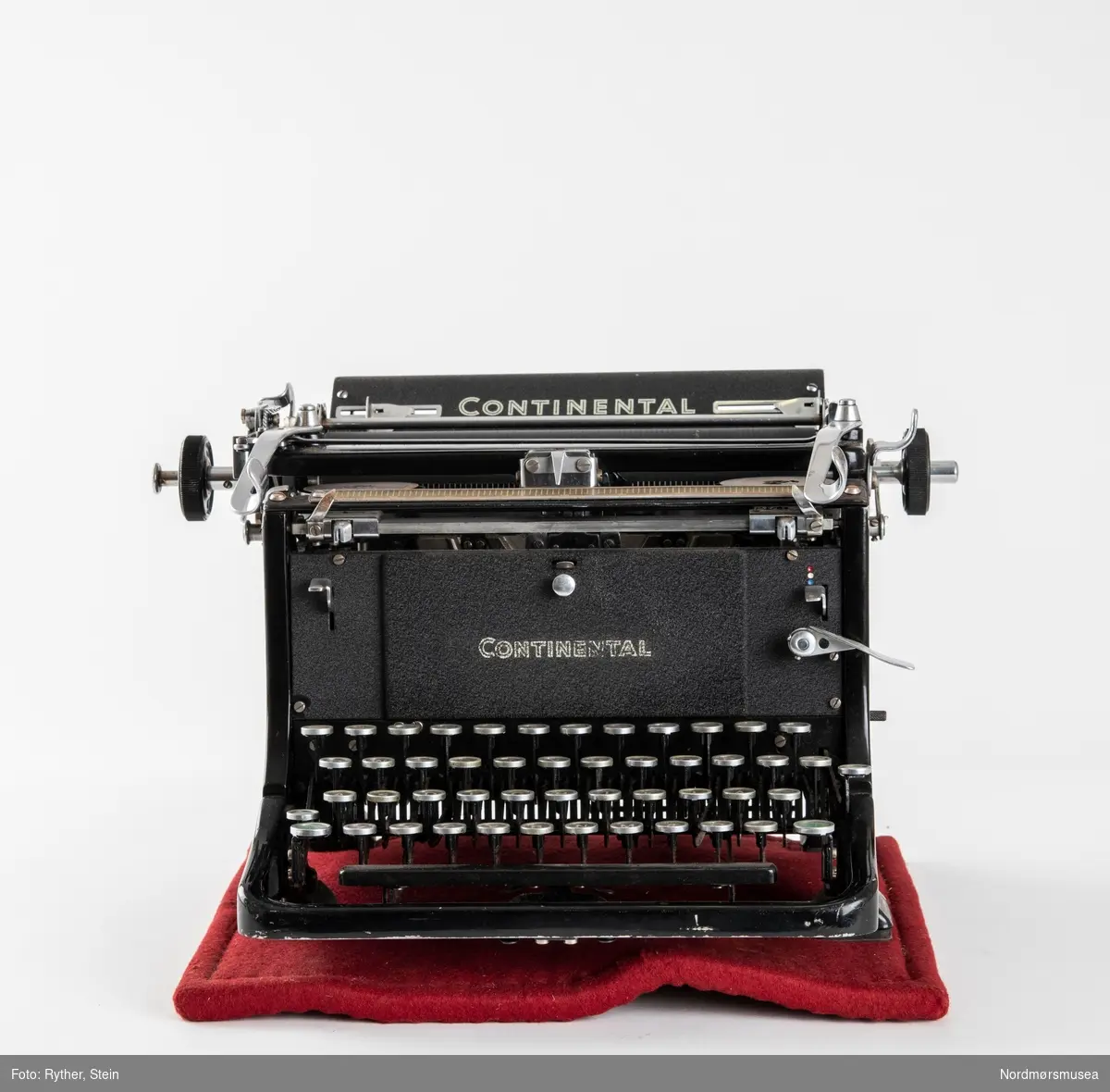 Continental Standard skrivemaskin fra 1951/52. Medfølger underlag med gummibunn og rød filt på toppen. Dekke i plast.