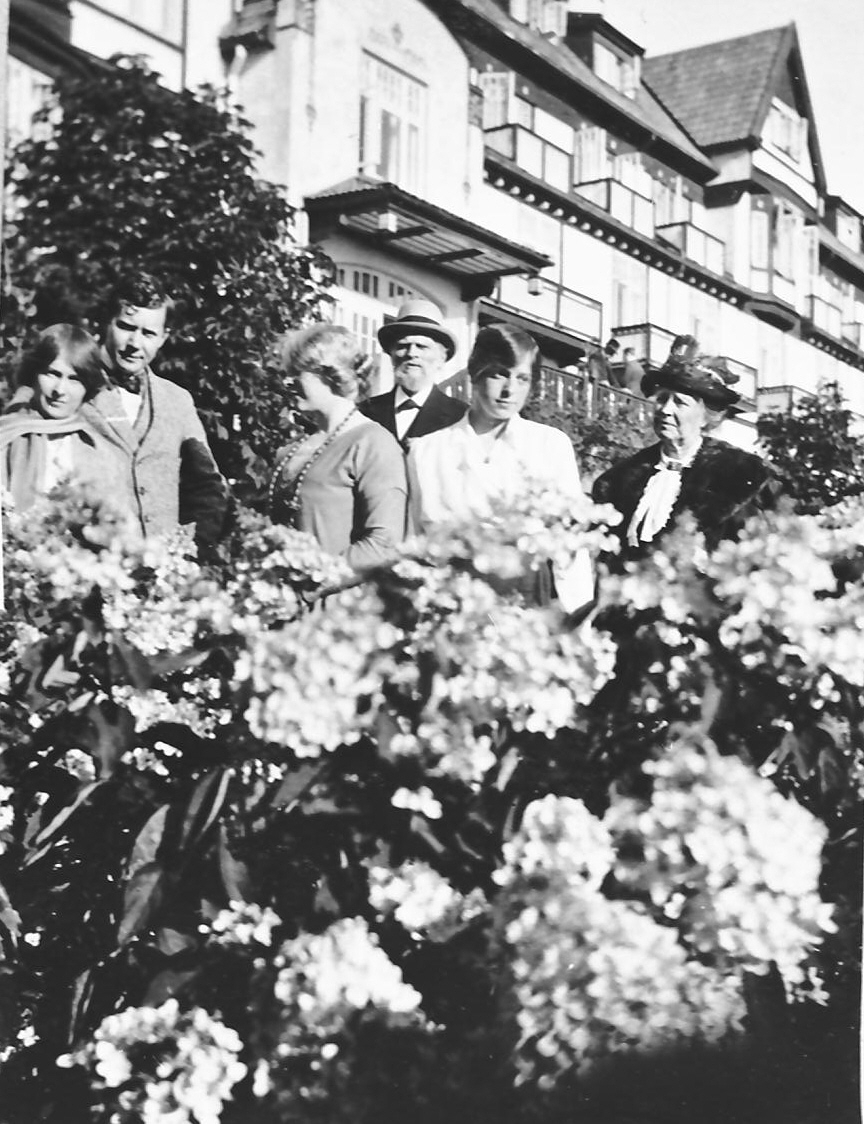 Familien J. B. Bull i hagen foran stort og fint hotell. 