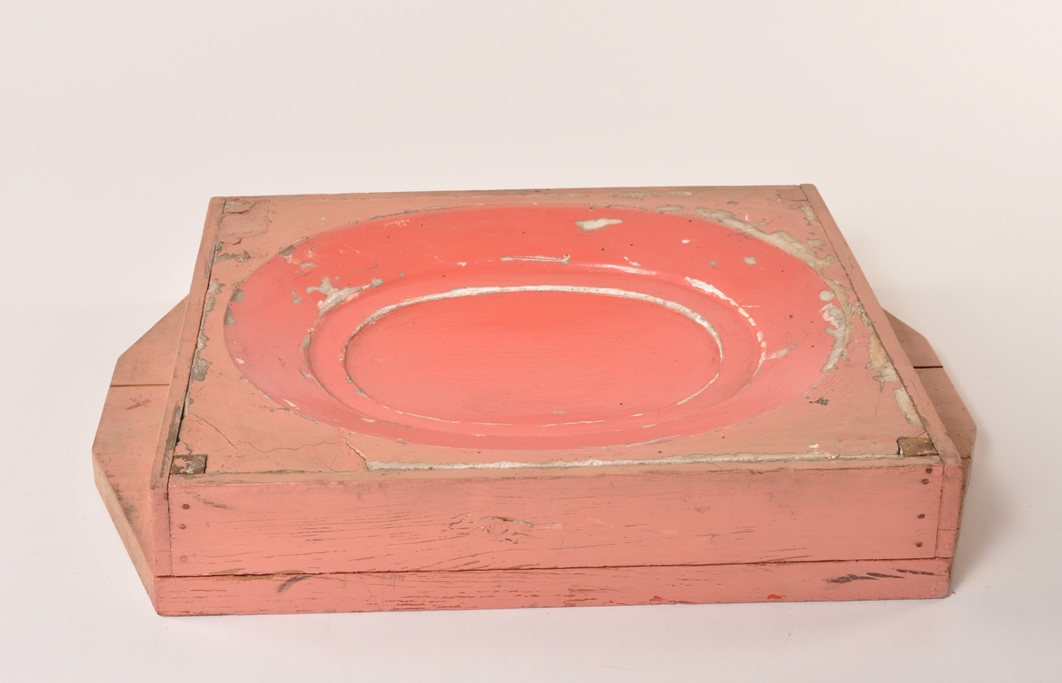 Modell av rosamalt og rødmalt tre i to deler til en grunn, oval fasong. Utydelig påskrift på den store delen [... ovn]