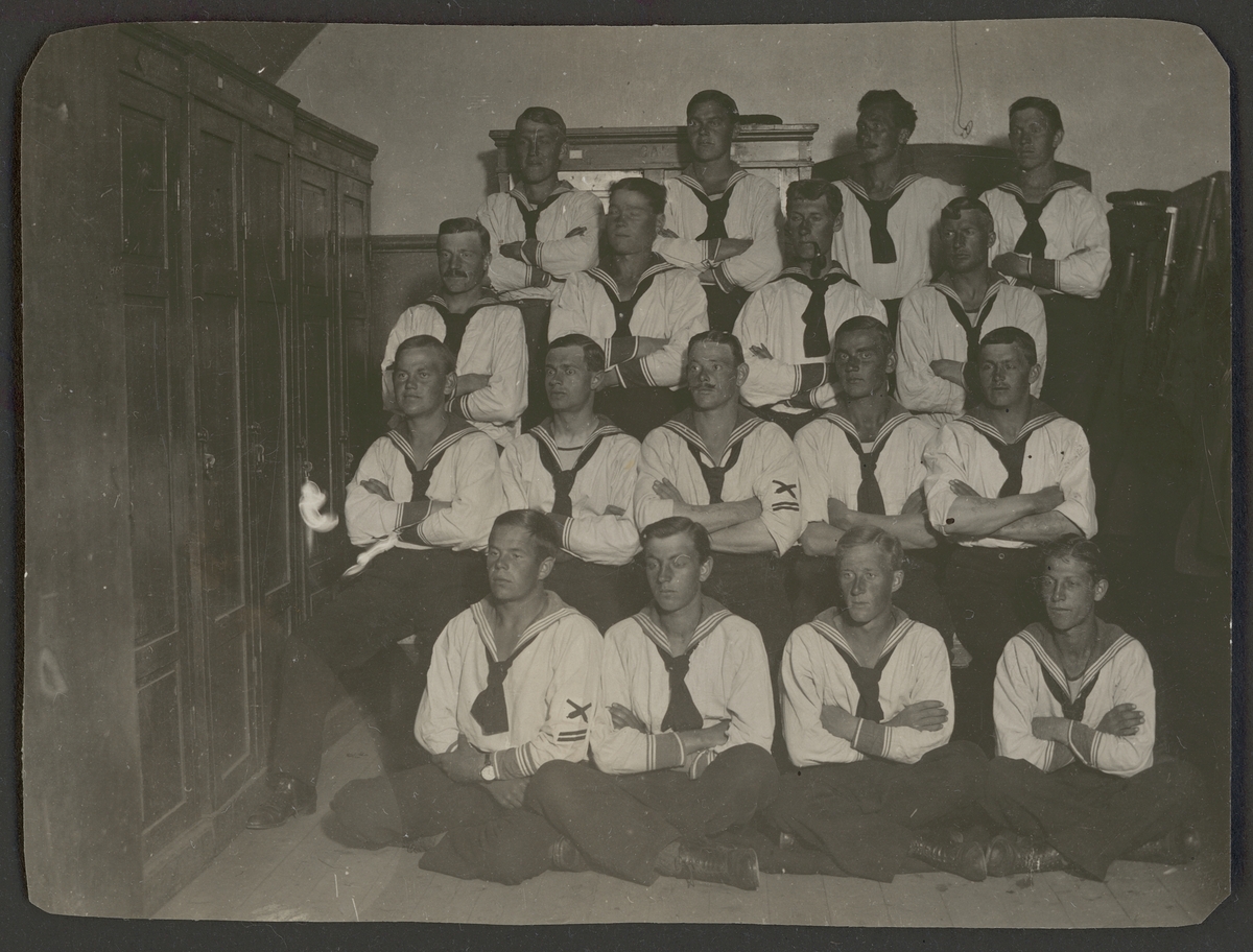 Bilden föreställer ett gruppfoto av soldater från kustartilleriet klädd i vita sjömanskostymer.