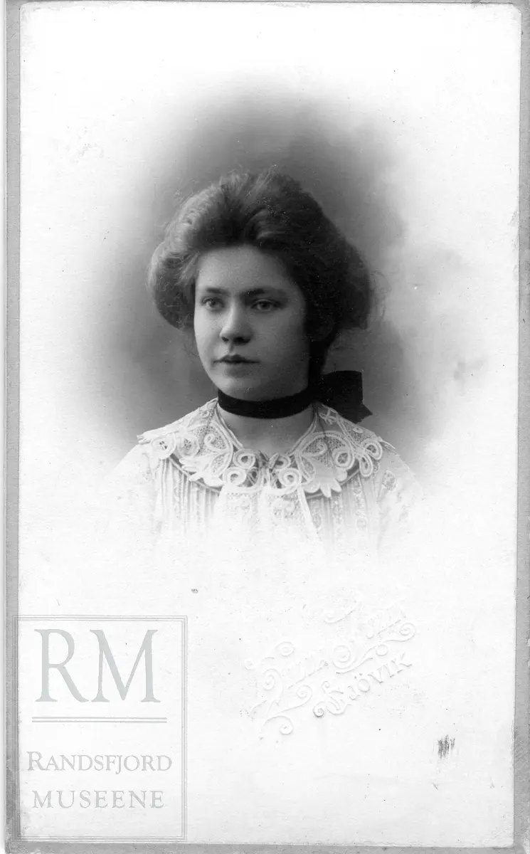 Brystbilde av ung kvinne i lys bluse og svart bred sløyfe i halsen.