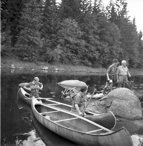 Två pojkar sitter i kanoter. De håller på att knuta sina flytkuddar runt bröstkorgen.