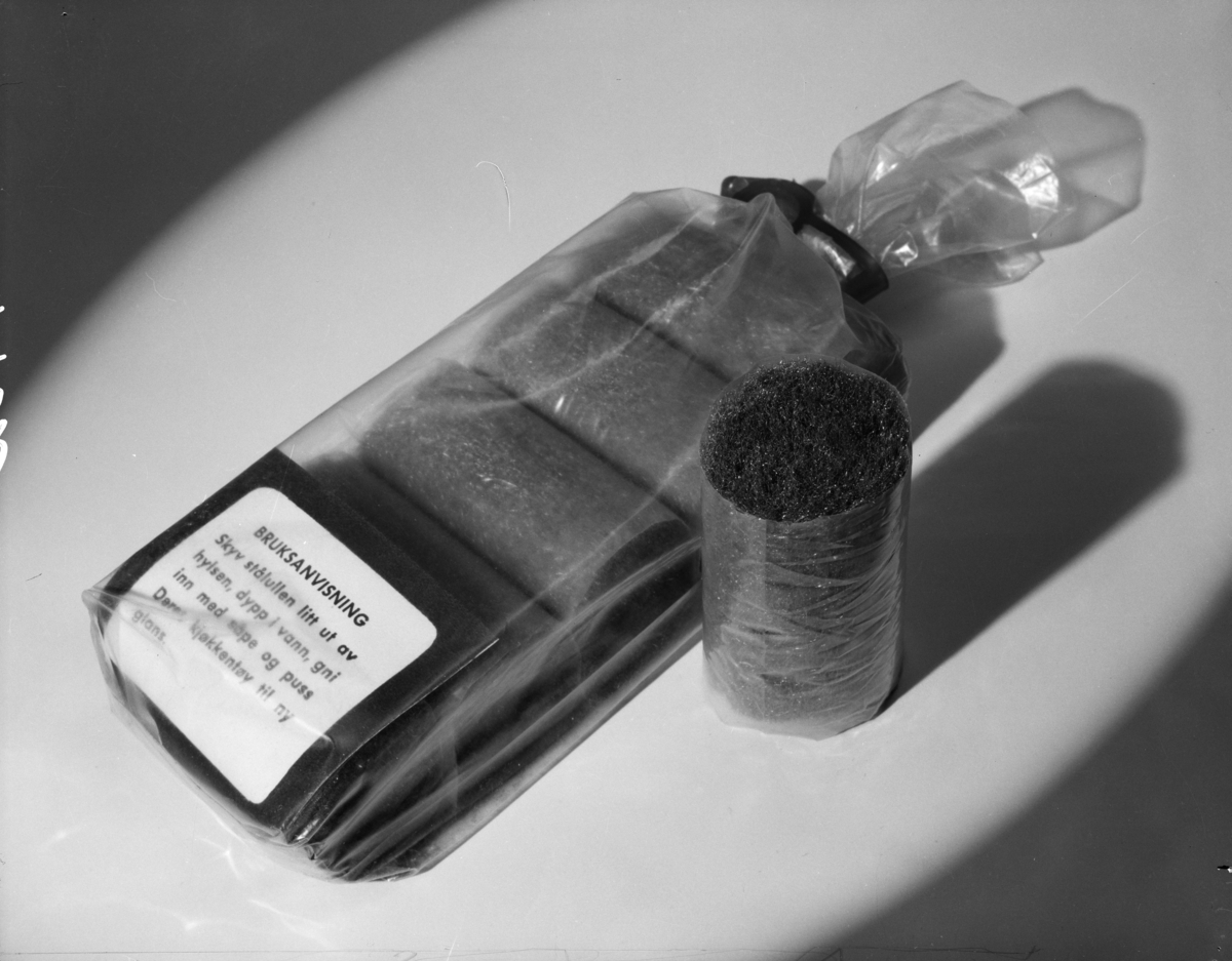 Produktfotografi av ruller med stålull innsatt med såpe, pakket i plast, til rengjøring av kjeler, publisert i Norsk Dameblad, trolig 1960-65.