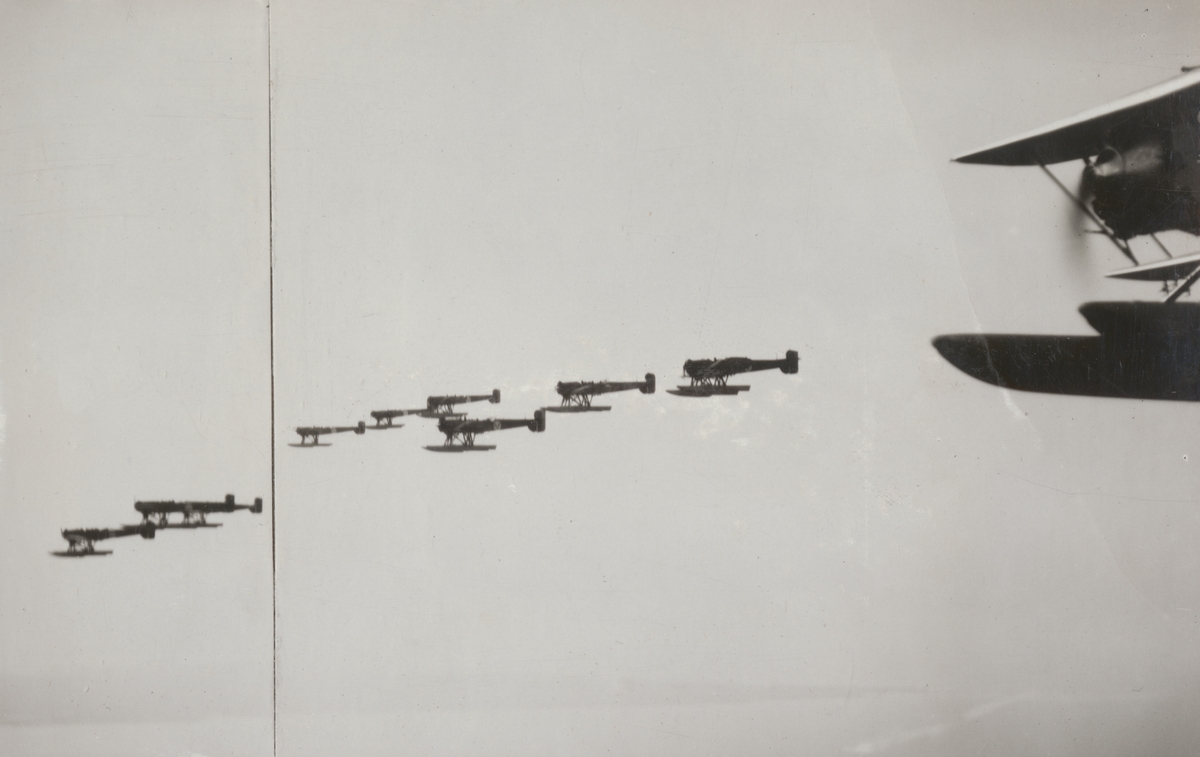 Fjärde spaningsdivisionens flygplan i luften, 1932. Nio flygplan S 5 flyger i formation. I förgrunden syns flygplan S 6 nummer 4392.
Flygbild.

Text vid foto: "1932 Sept. 4. SDIV 4392"