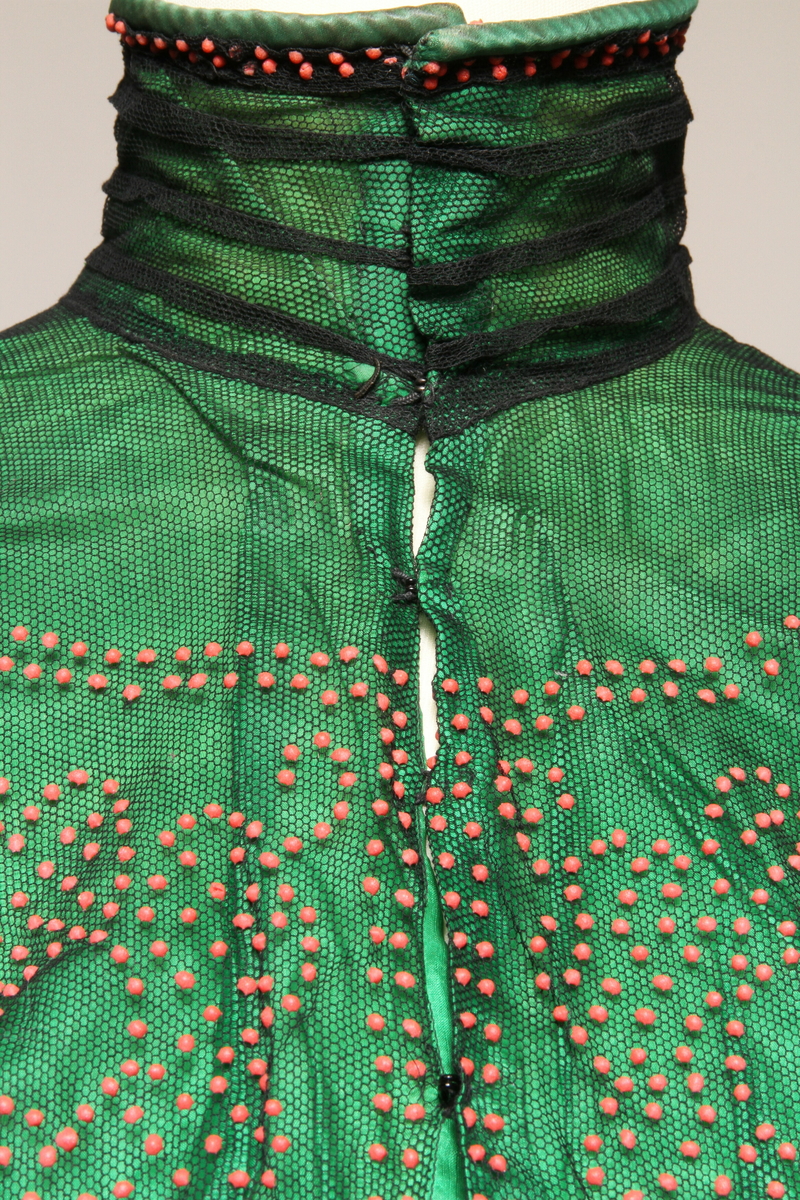 Grønn bluse i silke med svart tyll med pålimt rødt mønster. 