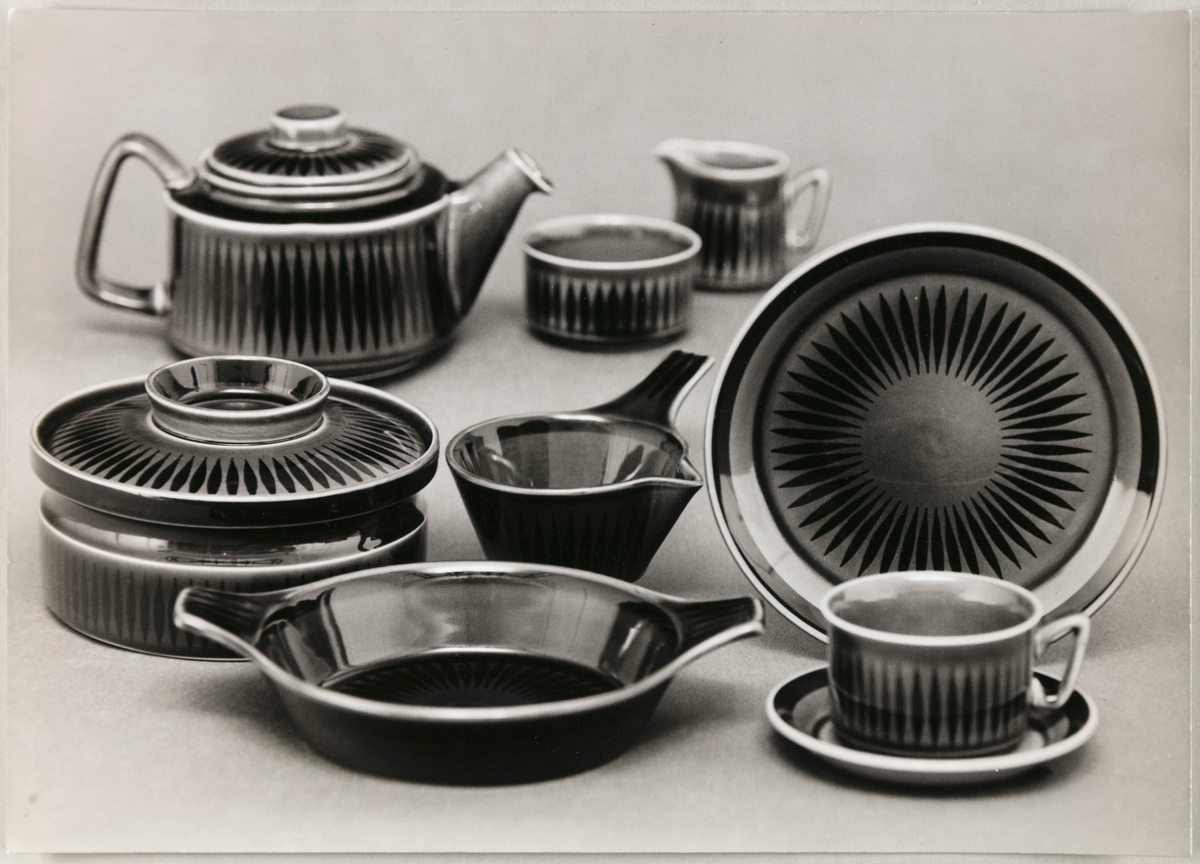 Reklamefoto av serviset "Jadar" fra Stavangerflint A/S. Avbildet sortiment viser en kopp med skål, tekanne, fløtemugge og sukkerskål, samt ildfaste former.