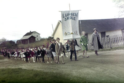 Fargebilde (blasse farger) av barnetog på 17. mai i Øvre Vang, fremst i toget bæres fana til Lunden skole.. Foto/Photo