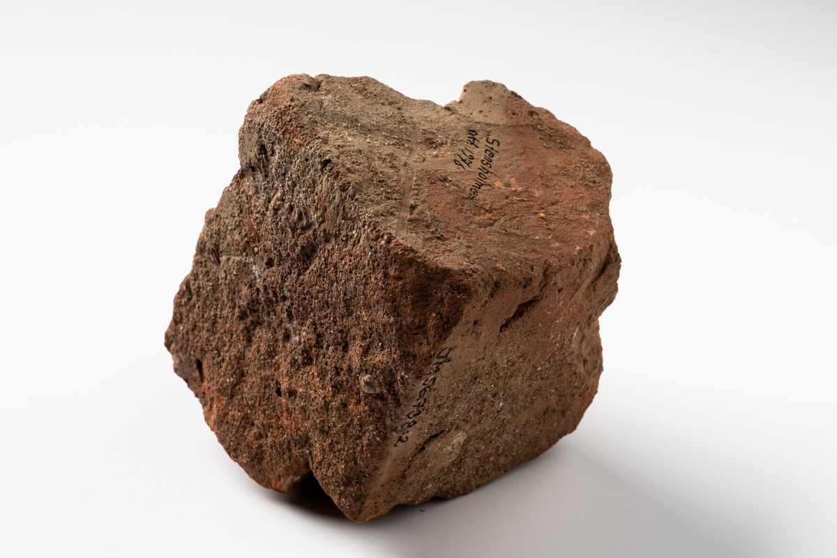 Tegelsten, del av, av rödbränande lera med tassavtryck av hund.