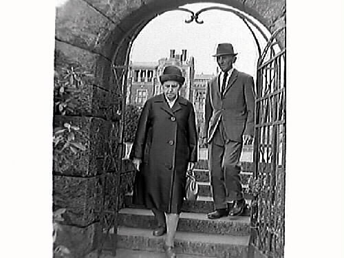 Knut och Maria Öberg går igenom en grindförsedd portal på gångstigen mot havet vid Tjolöholms slott, vilket syns i bakgrunden.