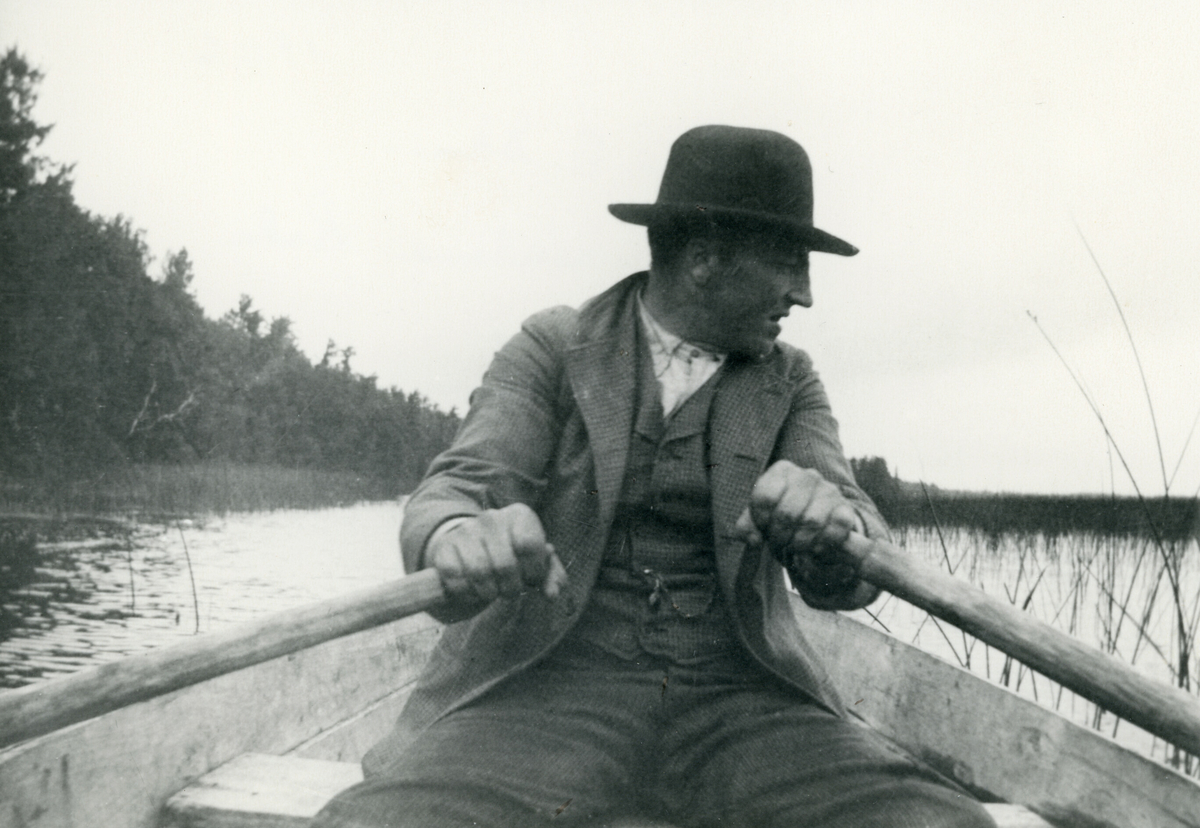 Ener E. Skoe ror ein båt på Island Lake i 1906.  Amerikabilde
