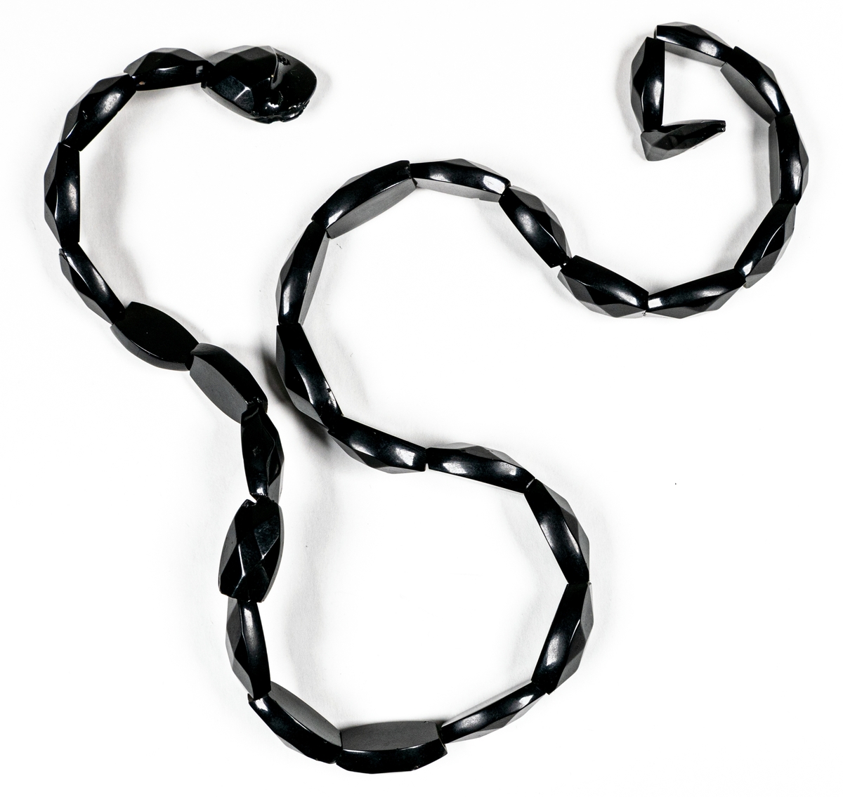 Armband av svart bakelit i form av en orm med fasetterade länkar.