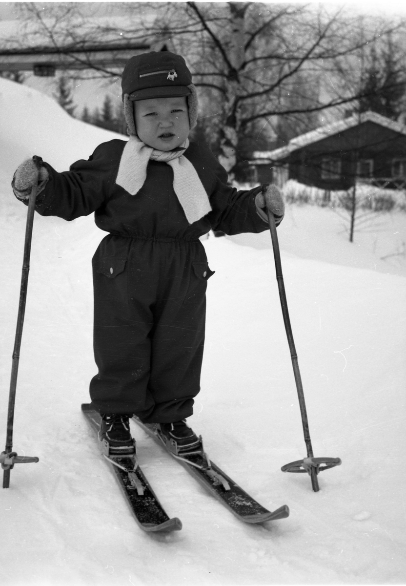 En liten gutt på ski i helfigur.