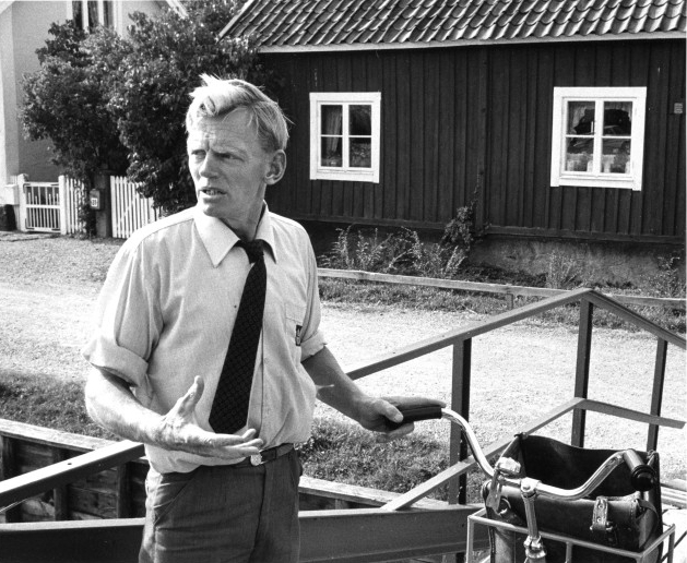 På sin brevbäringstur träffar Nils Olsson en postkund (utanför
bild) som han re-sonerar med. Han har varit i jobbet i jobbet sen
1961 och bott i Trosa-trakten i 25 år. Därför känner Nils de flesta i
sitt distrikt.